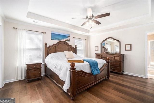 bedroom featuring ensuite bath, ceiling fan, a raised ceiling, dark hardwood / wood-style floors, and crown molding