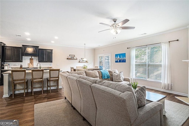 living room with dark hardwood / wood-style floors, ceiling fan, sink, and crown molding