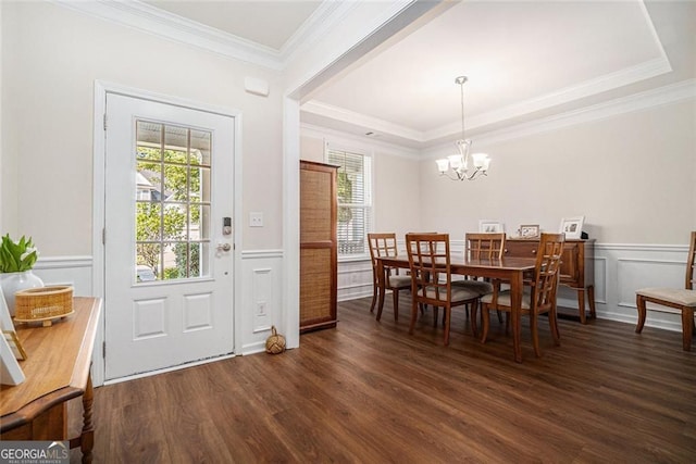 dining room featuring a raised ceiling, a chandelier, dark wood-type flooring, and ornamental molding