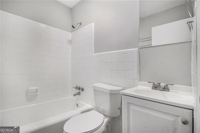 full bathroom featuring vanity, toilet, tile walls, and tiled shower / bath combo