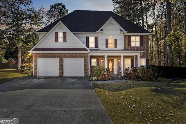 view of front of home with covered porch, a yard, and a garage