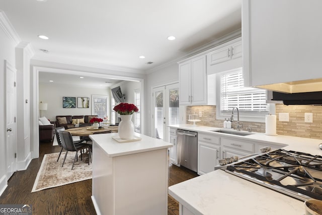 kitchen with a center island, backsplash, white cabinets, sink, and appliances with stainless steel finishes