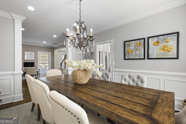 dining room featuring dark hardwood / wood-style flooring, an inviting chandelier, ornate columns, and ornamental molding