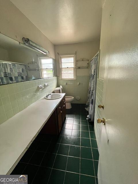 bathroom featuring tile patterned floors, vanity, toilet, and tile walls