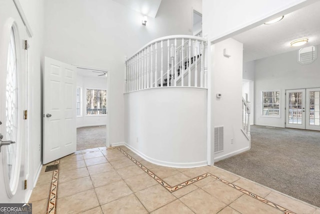 entrance foyer featuring light carpet, ceiling fan, and a high ceiling