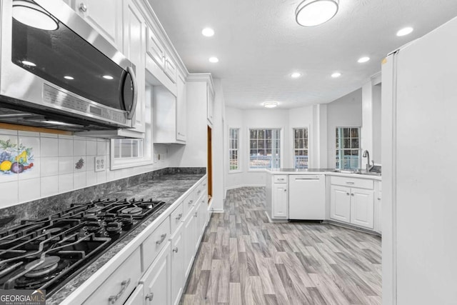 kitchen featuring dishwasher, kitchen peninsula, light wood-type flooring, white cabinetry, and gas cooktop