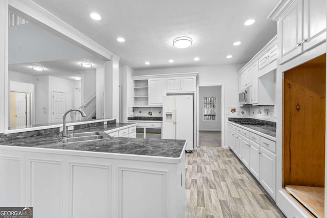 kitchen with sink, kitchen peninsula, light hardwood / wood-style flooring, white fridge with ice dispenser, and white cabinetry