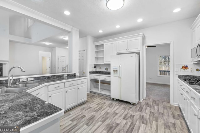 kitchen featuring white cabinetry, white fridge with ice dispenser, light hardwood / wood-style flooring, and sink