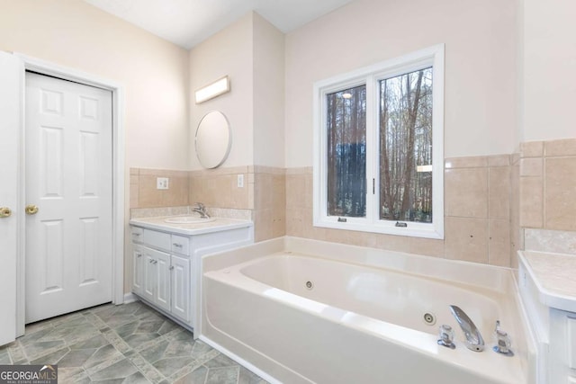 bathroom featuring vanity, a tub, and tile walls