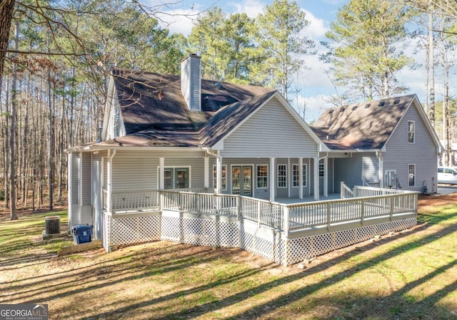 rear view of property with a lawn, a wooden deck, and central AC unit