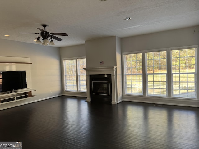 unfurnished living room featuring a wealth of natural light, ceiling fan, and a textured ceiling