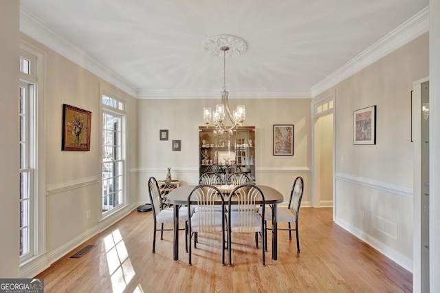 dining room featuring ornamental molding, light wood-type flooring, and a chandelier