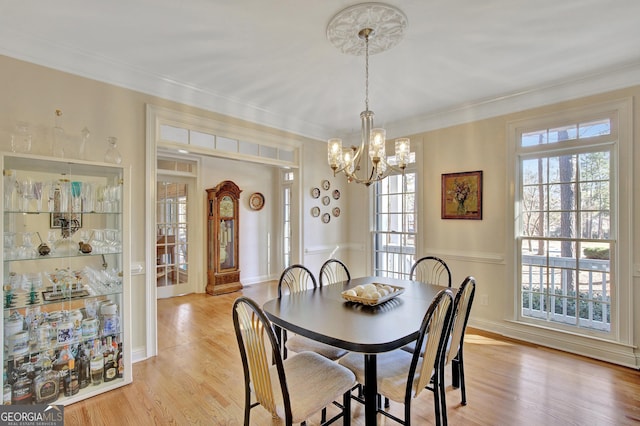 dining area with crown molding, a notable chandelier, and light hardwood / wood-style floors