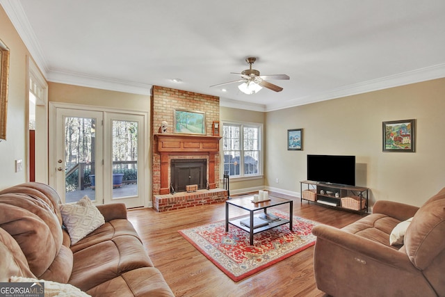 living room featuring ceiling fan, ornamental molding, a fireplace, and light wood-type flooring