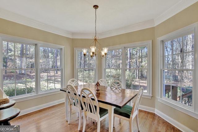 dining space featuring an inviting chandelier, ornamental molding, and light hardwood / wood-style flooring