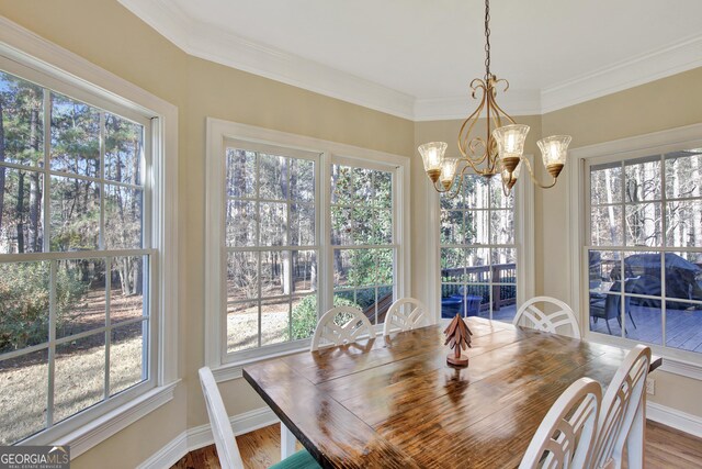 dining space featuring hardwood / wood-style flooring, crown molding, a healthy amount of sunlight, and an inviting chandelier