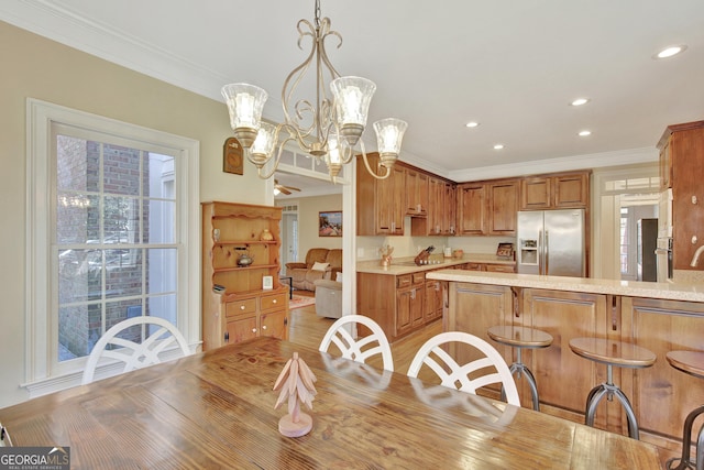 dining space with an inviting chandelier, ornamental molding, and light hardwood / wood-style floors