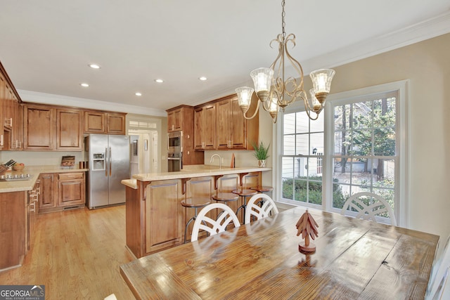 kitchen featuring a breakfast bar, decorative light fixtures, ornamental molding, light hardwood / wood-style floors, and stainless steel appliances