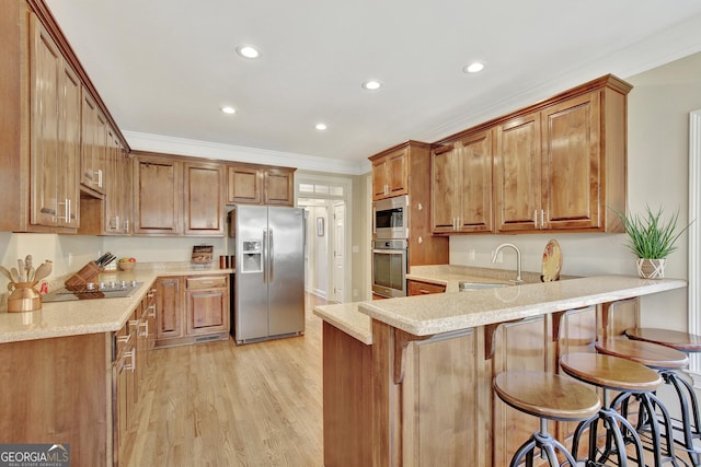 kitchen with appliances with stainless steel finishes, sink, a kitchen bar, kitchen peninsula, and crown molding