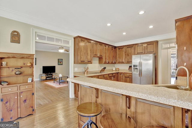 kitchen with sink, crown molding, stainless steel fridge, and a kitchen breakfast bar