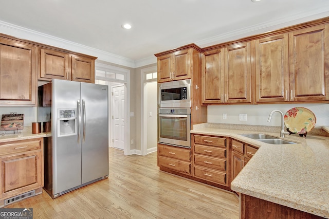 kitchen featuring sink, crown molding, stainless steel appliances, light stone counters, and light hardwood / wood-style floors