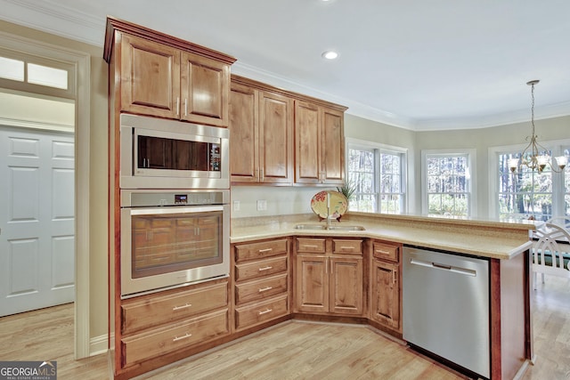 kitchen featuring sink, light wood-type flooring, ornamental molding, a notable chandelier, and stainless steel appliances