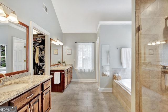 bathroom featuring tiled tub, crown molding, vanity, vaulted ceiling, and tile patterned floors