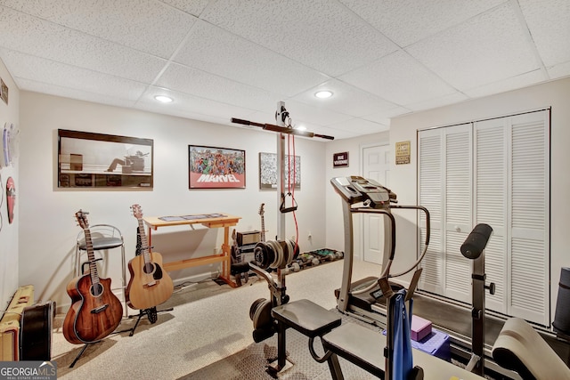 workout room featuring a paneled ceiling and carpet flooring