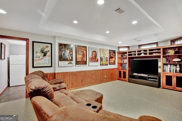 living room featuring a raised ceiling, carpet, and wood walls