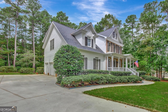 view of front facade featuring a porch, a garage, and a front yard