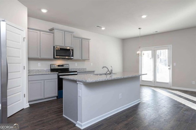 kitchen with dark wood-type flooring, sink, gray cabinets, an island with sink, and appliances with stainless steel finishes