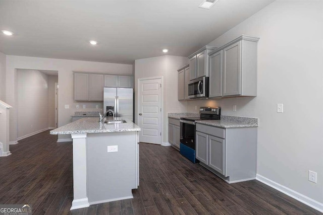 kitchen with gray cabinetry, sink, stainless steel appliances, dark hardwood / wood-style floors, and a kitchen island with sink