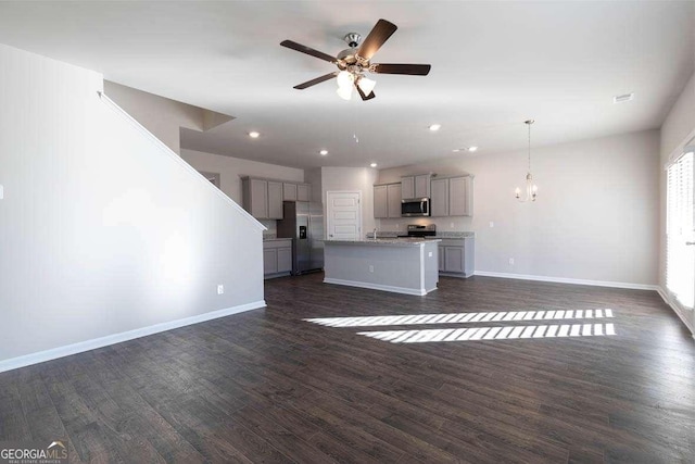 unfurnished living room featuring ceiling fan with notable chandelier and dark hardwood / wood-style flooring