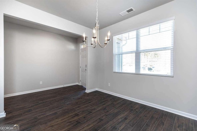 spare room with dark wood-type flooring and an inviting chandelier