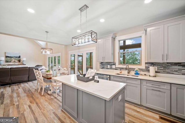 kitchen with decorative light fixtures, backsplash, sink, and gray cabinetry