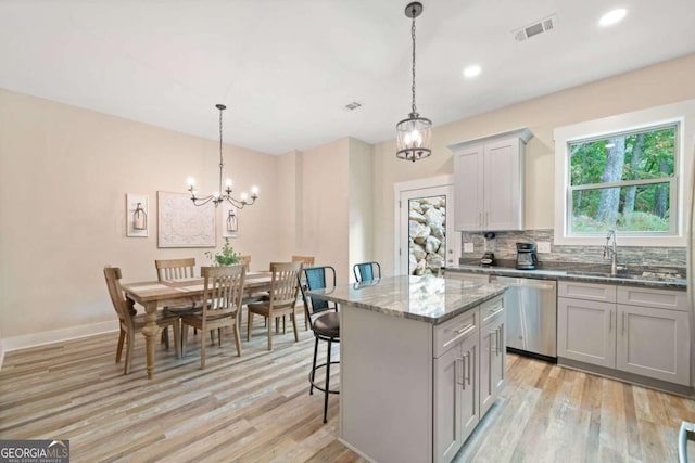 kitchen with stainless steel dishwasher, decorative light fixtures, gray cabinetry, and a center island