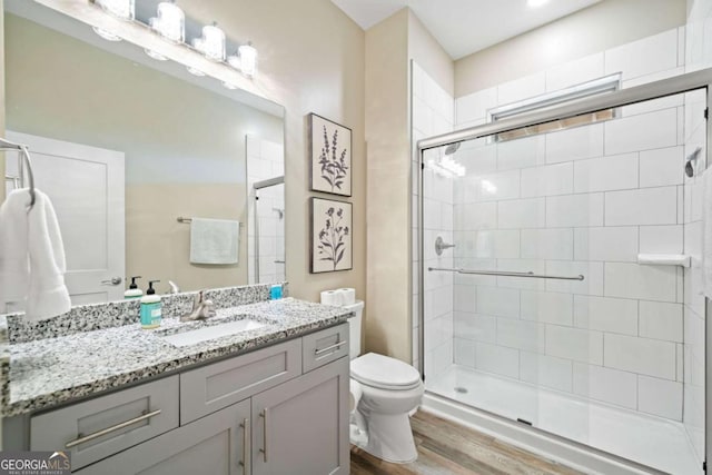 bathroom featuring toilet, walk in shower, hardwood / wood-style floors, and vanity