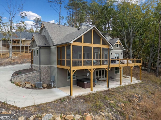 rear view of property with a sunroom, cooling unit, a hot tub, and a patio