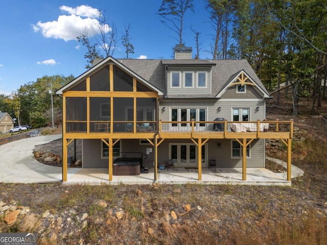 rear view of house with a hot tub, a patio area, and a sunroom