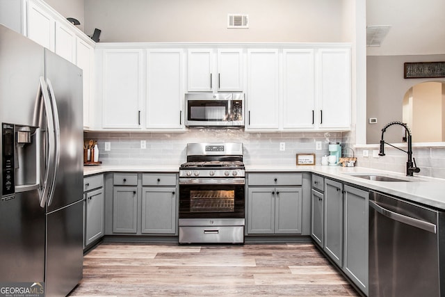 kitchen featuring stainless steel appliances, white cabinetry, gray cabinetry, and sink