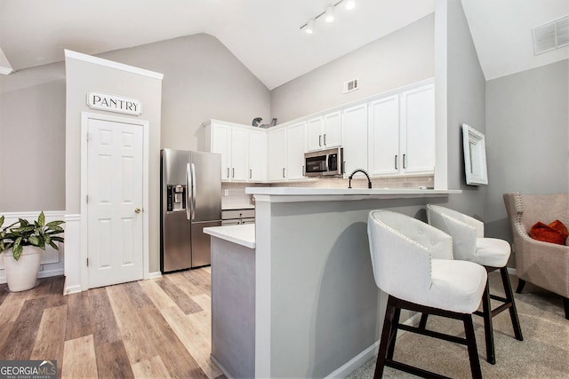 kitchen featuring white cabinets, a kitchen breakfast bar, kitchen peninsula, and stainless steel appliances