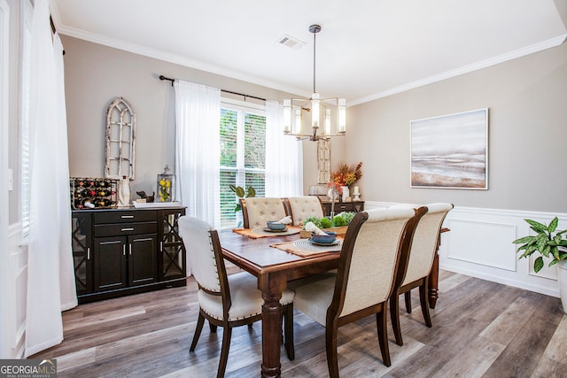 dining area with crown molding, light hardwood / wood-style flooring, and a chandelier