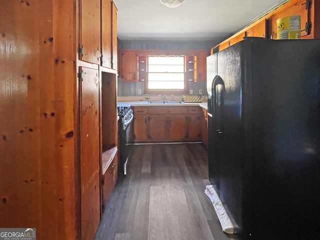 kitchen with dark hardwood / wood-style floors, black fridge with ice dispenser, sink, and stainless steel range with gas stovetop