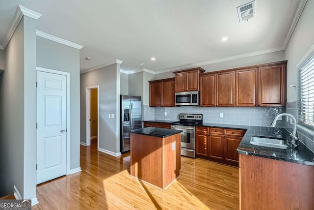 kitchen featuring dark stone countertops, a kitchen island, sink, and stainless steel appliances