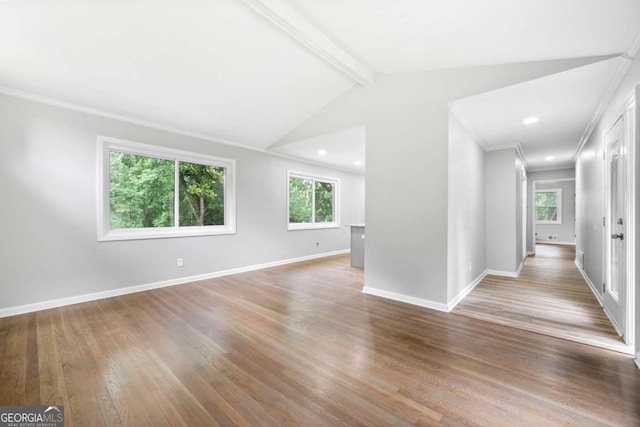 empty room featuring vaulted ceiling with beams, light hardwood / wood-style floors, a wealth of natural light, and ornamental molding