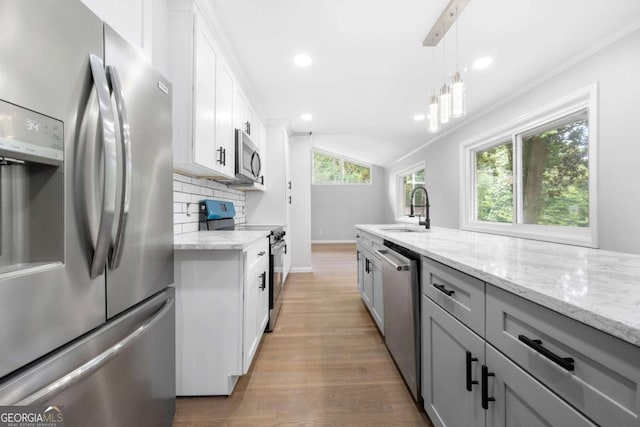 kitchen with backsplash, light stone counters, stainless steel appliances, pendant lighting, and white cabinets