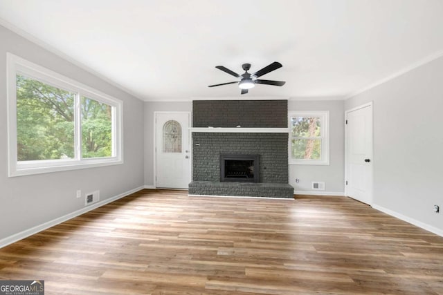 unfurnished living room with a fireplace, wood-type flooring, ceiling fan, and crown molding