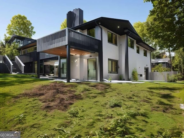 rear view of property featuring a patio area, a yard, and a deck