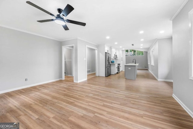 unfurnished living room featuring ceiling fan, light hardwood / wood-style flooring, sink, and ornamental molding