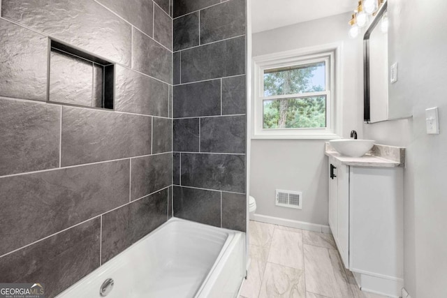 bathroom featuring a tile shower, vanity, and toilet